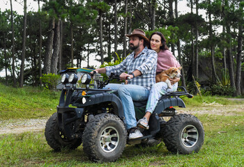 Portrait of young married couple sitting on a quad bike in the forest © Tatiana