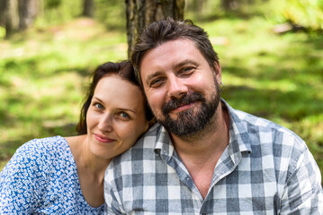 Fototapeta premium Portrait of young married couple sitting in the forest on a sunny day