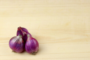 Shallot isolated on wooden board. Red or purple onion.