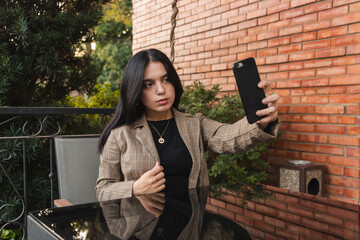 Young enterprising girl taking a selfie, sitting in an outdoor cafe.