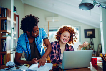 Two young people studying together at home and using the laptop