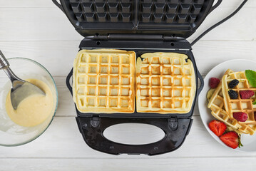 close-up of the process of making Belgian waffles in a waffle iron at home.