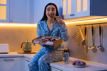 Young woman eating pizza in kitchen at night. Bad habit