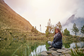 latin woman on vacation sitting on the shores of a lake on high altitude in bolivia