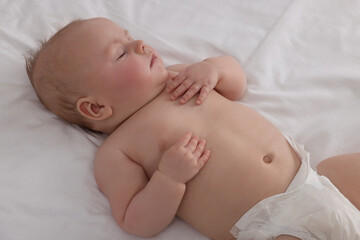 Cute newborn baby in diaper sleeping on bed at home