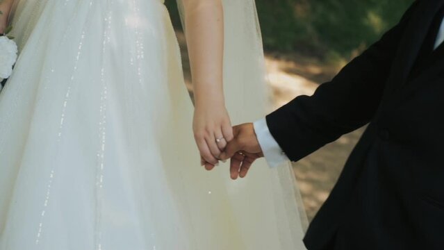 Couple holding hands. Bride and groom holding hands and walking.Holding hands together. Slow motion	