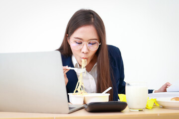 Portrait of a beautiful girl, an employee or an executive in an office wearing a blue suit, eating at a desk. business concept