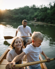 Brother and sister learning to paddle canoe with father