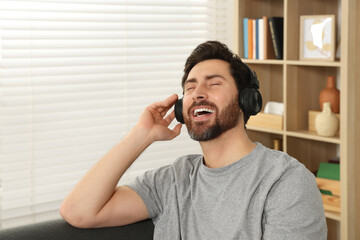 Happy man listening music with headphones indoors