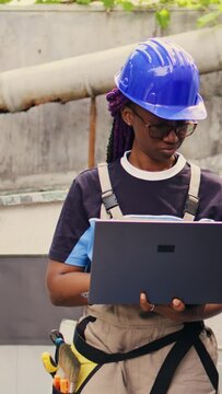 Vertical video Experienced engineer working on external hvac system, holding laptop. Meticulous wireman optimizing outdoor condenser performance, ensuring it operates at maximum capacity