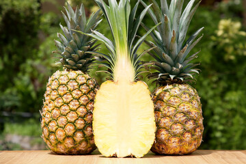 Delicious ripe pineapples on wooden table outdoors