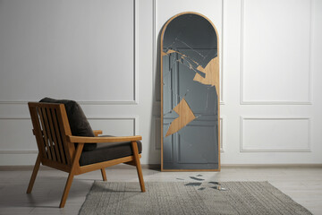 Broken mirror with many cracks and armchair in room