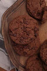 Board with tasty chocolate cookies on beige tablecloth, top view