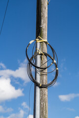 Fibre optic cables on telegraph pole against blue sky with clouds background, telecommunication and infrastructure editorial illustration.
