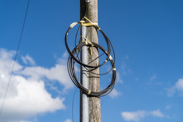 Fibre optic cables on telegraph pole against blue sky with clouds background, telecommunication and...