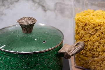 Granite frying pan with glass on black induction stove against grey wall. Cooking pot.