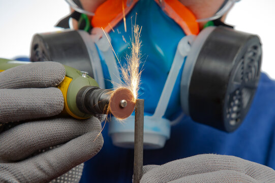 Male locksmith worker processes metal with engraving drill cutting. The work of the dremel engraving electric tool. Industrial metal processing industry