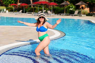 The overweight woman dressed swimming suit swimming the pool, have a vacation in a luxury hotel