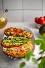 Toasted sourdough bread with grilled asparagus, avocado, tomatoes, radish and herbs for single serving. Avocado toast. Breakfast idea. Healthy food concept.