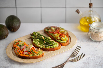 Toasted sourdough bread with grilled asparagus, avocado, tomatoes, radish and herbs for single serving. Avocado toast. Breakfast idea. Healthy food concept.