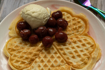 Herzwaffeln mit Vanille Eis und Kirschen. Ein Traum in Weiß rot auf braun