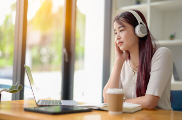 Portrait of teenage smiling girl using a laptop and wearing headphones, study online via video conferencing, enjoy with movie.