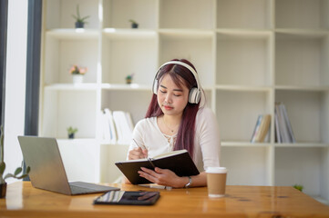 Portrait of teenage smiling girl using a laptop and wearing headphones, study online via video conferencing.