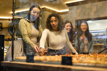 group of friends in a pizzeria choosing pizza