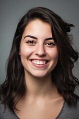  headshot of a happy young woman looking at the camera on gray background
