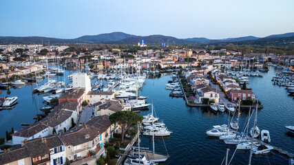 Fototapeta na wymiar Port Grimaud harbor in France in springtime with yachts and sailboats and Mediterranean Sea in the evening, drone shot, Cote d'Azur