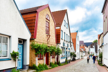 Gable Houses with high roses on a house wall in the fishing village Holm in Schleswig, Germany - obrazy, fototapety, plakaty