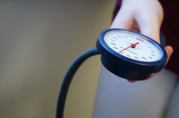 Hand von Ärztin hält Blutdruckmessgerät 