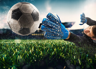 Close up of a goalkeeper catching the ball in the stadium during a football game - obrazy, fototapety, plakaty
