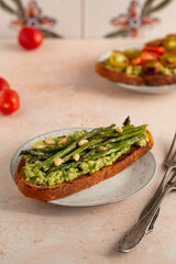 Toasted sourdough bread with grilled asparagus, avocado, tomatoes and herbs for single serving. Avocado toast. Breakfast idea. Healthy food concept.
