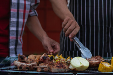 Meat and skewers ingredients for barbecue party are placed on grill to cook barbecue and make it ready for family to join barbecue party tonight.  party background image has Copy Space for text.