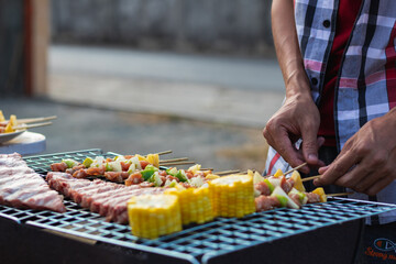 Meat and skewers ingredients for barbecue party are placed on grill to cook barbecue and make it ready for family to join barbecue party tonight.  party background image has Copy Space for text.