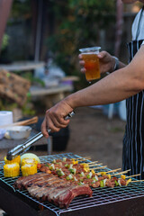 Meat and skewers ingredients for barbecue party are placed on grill to cook barbecue and make it ready for family to join barbecue party tonight.  party background image has Copy Space for text.