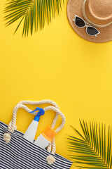 Summer retreat by the ocean concept. Top view vertical arrangement of beach bag with sunscreen...