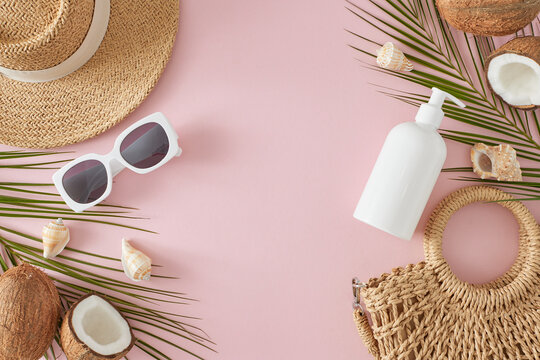 The idea of a coastal recreational getaway. Top view composition of sunscreen bottle, sun hat, eyewear, straw handbag, coconuts, palm leaves, seashells on pastel pink background with space for advert