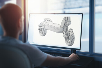 An engineer works on a computer on an electric scooter - a 3D model of the vehicle presented as an...