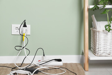 Different electrical plugs in socket and power strip on floor indoors. Space for text