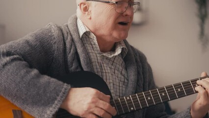 Romantic senior man playing acoustic guitar and singing song at home, music - Powered by Adobe