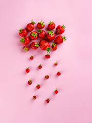 Cloud and rain from strawberries on a pink background. Vertical orientation, top view.