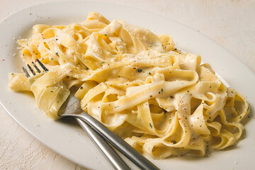 Fettuccine, tagliatelle, in creamy garlic sauce, Italian traditional cuisine, pasta carbonaro,