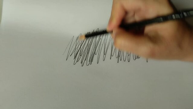Un primer plano de una mano con un lápiz de madera dibujando  en una hoja de color blanco.