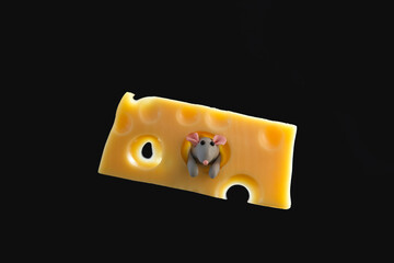 Small plasticine gray mouse sticks out of a piece of cheese.