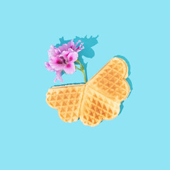 Freshly baked homemade heart shape waffles with pink geranium flowers on turquoise blue background. Minimal floral concept of love and sweet food. Flat lay.
