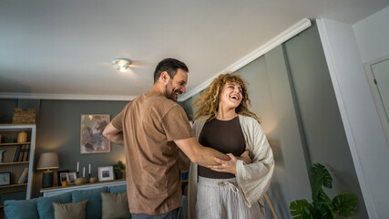 Happy couple adult caucasian man woman husband and wife dance at home