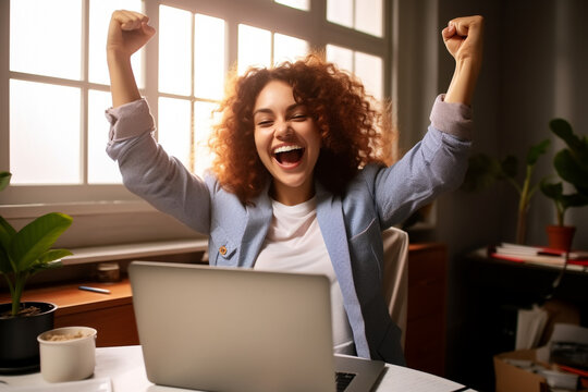 Joyful business woman freelancer entrepreneur smiling and rejoices in victory while sitting at desk and working at laptop after finishing project in home office. High quality photo