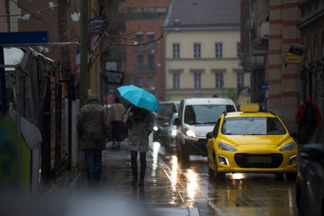 Rain in a city, cars and person with umbrella